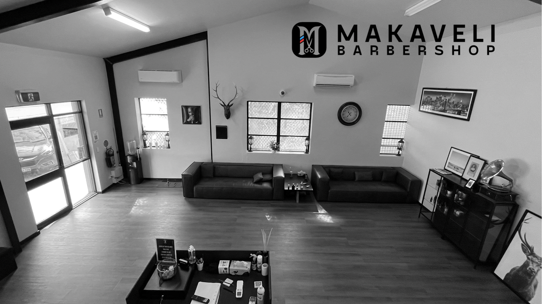 Inside Makaveli Barber Shop: couches, mirrors and the Makaveli sign on the back wall