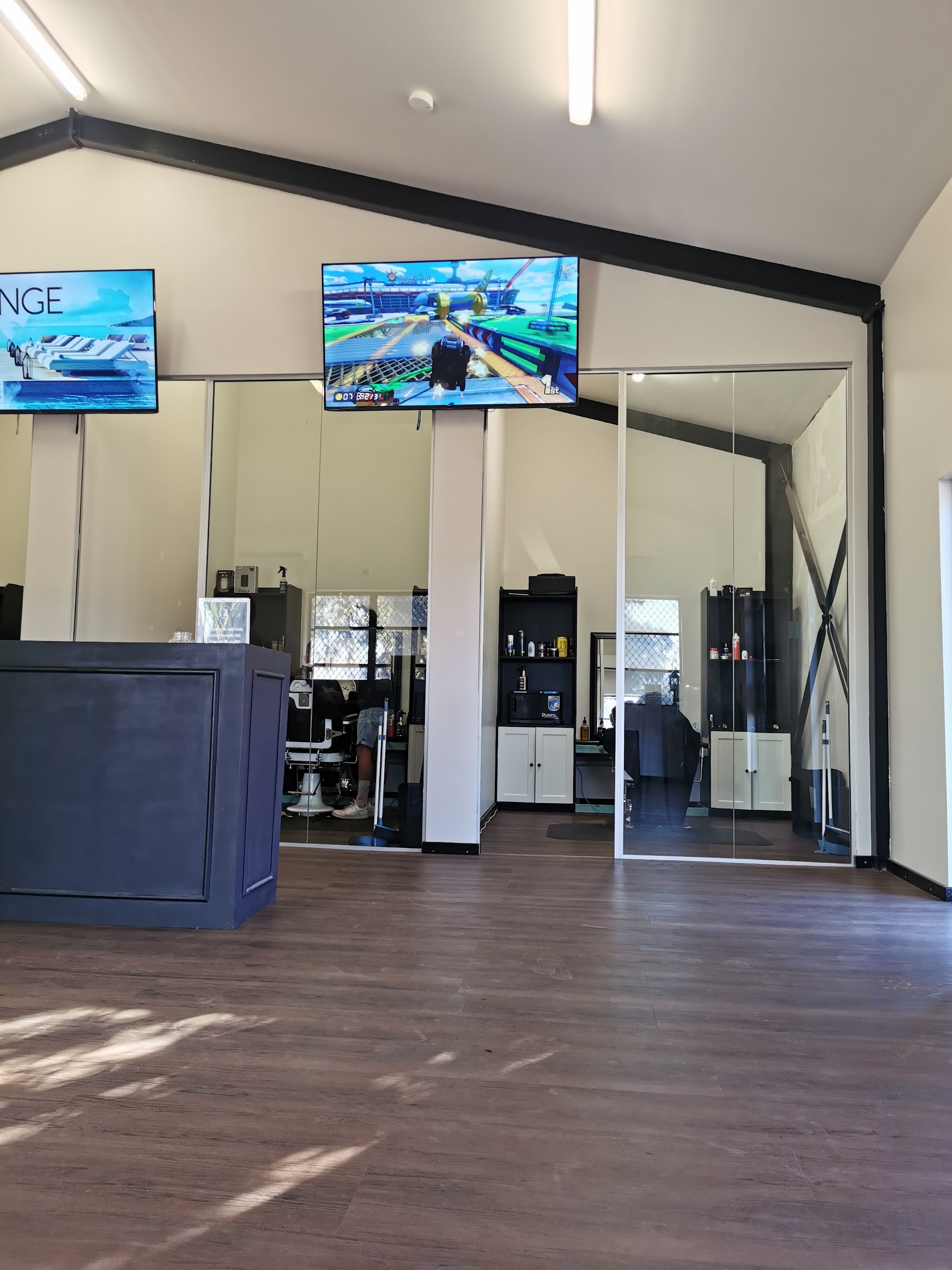 The shop floor: glass stations, mirrors and the screens above the chairs