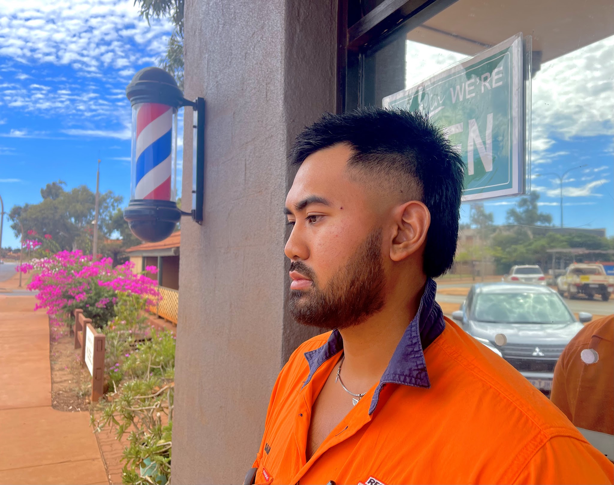 Fresh fade cut outside the shop, barber pole on the wall